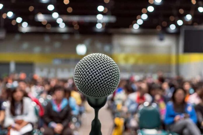 Microphone on stage facing a blurred audience