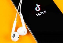 DOJ Greenlights TikTok — What Changed? Smartphone with TikTok app and white wired earbuds on yellow background