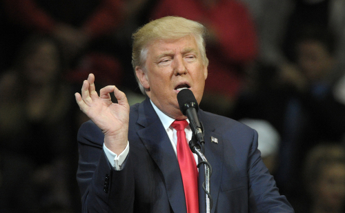 A man speaking into a microphone with a hand gesture during a speech