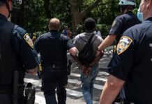 Planned Attack Rocks FBI Hub Police escort a handcuffed man across a city street
