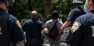 Police escort a handcuffed man across a city street