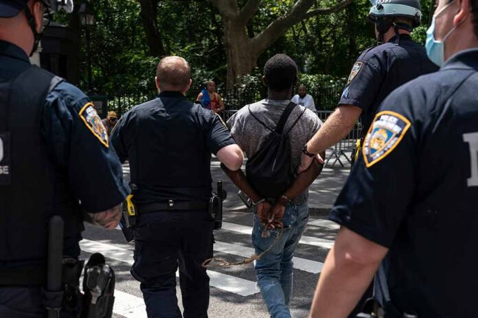 shutterstock_1777046294 Police escort a handcuffed man across a city street