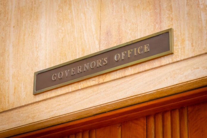 A,Formal,And,Official,Sign,On,The,Door,Of,The Governor's Office sign above a wooden doorway
