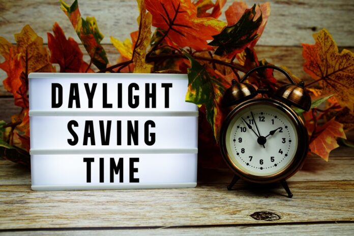 Daylight,Saving,Time,Text,With,Alarm,Clock,And,Maple,Leaf California state flag waving near a white domed capitol building