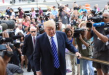 Questions Follow Trump’s Foreign Business Fee A public figure surrounded by a crowd of photographers and onlookers