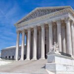 Supreme Court building with columns and statues outside.