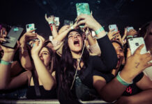 Concert crowd cheering and taking photos with phones.