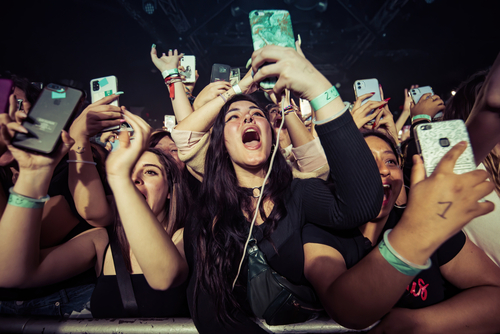 Concert crowd cheering and taking photos with phones.