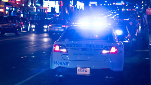 Police car with lights on in city at night.