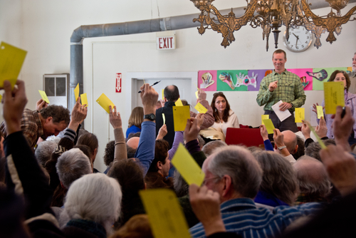 People holding up voting cards at a meeting.