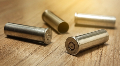 Four empty bullet casings on a wooden surface.