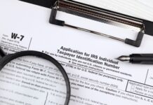 IRS W-7 form with magnifying glass and pen.