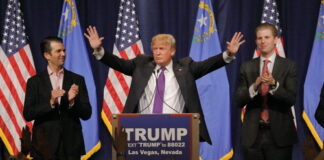 Donald Trump at a rally with his sons applauding.