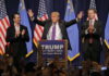 Donald Trump at a rally with his sons applauding.