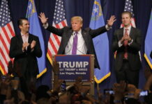 Donald Trump at a rally with his sons applauding.